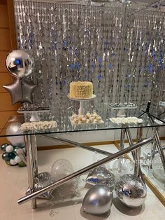 a glass table topped with lots of desserts next to a wall covered in crystal beads