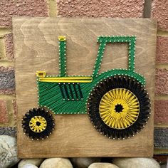 a wooden sign with a green and yellow tractor painted on it's side next to some rocks