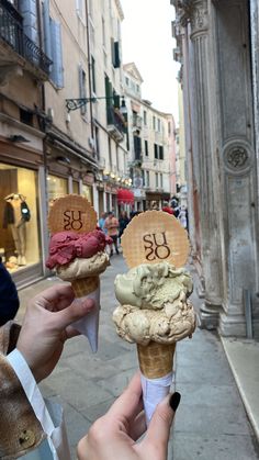 two ice cream cones with numbers on them are being held up in the air by someone's hand