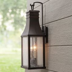 two light outdoor wall lantern on the side of a house with grass in the background