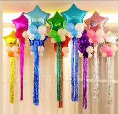 balloons and streamers are hanging from the ceiling in front of a window with curtains