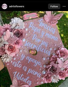 a pink graduation cap decorated with flowers and words on the side, in front of some grass