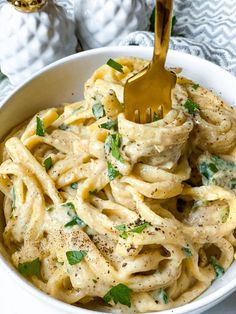 a white bowl filled with pasta covered in pesto