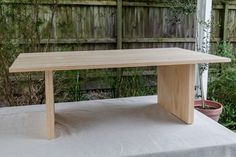 a wooden table sitting on top of a white cloth covered ground next to a fence