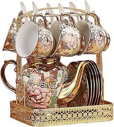 an ornately decorated tea set with cups and saucers in a holder on a white background