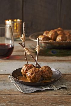 two meatballs on a plate with some sticks sticking out of them and another dish in the background