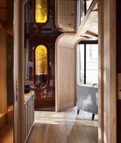 a hallway leading to a living room with wooden floors and walls, along with an arched doorway that leads into the dining area