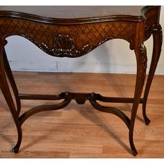 an ornate wooden table with carvings on the top and bottom, sitting on a hard wood floor