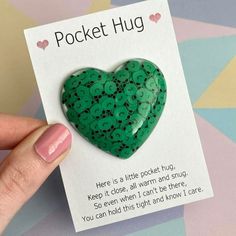 a green heart shaped brooch sitting on top of a card