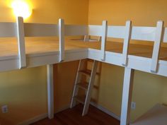 there are two bunk beds with ladders on the bottom and one is white in color