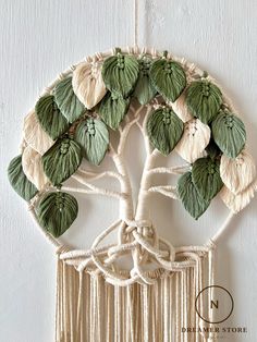 a white wall hanging with green leaves and a tree in the center, on a white background