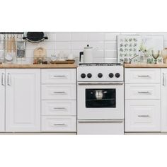 a white stove top oven sitting inside of a kitchen next to a wooden countertop