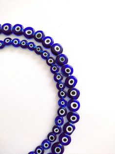 three strands of blue glass beads with an evil eye design on the front and back