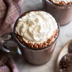 two mugs filled with whipped cream and chocolate cookies