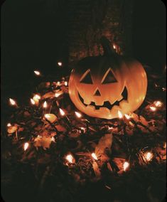 a jack o lantern is lit up in the dark with many small lights around it