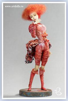 a doll with red hair is standing on a pedestal