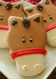 some cookies are shaped like animals on a white plate with red ribbon around their necks