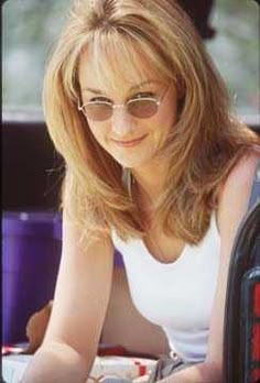 a woman sitting in the back seat of a car with sunglasses on her head and smiling