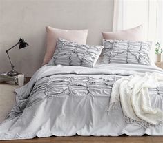 a bed with two pillows and blankets on top of it, in front of a white background