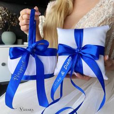 the bride is holding her blue and white wedding ring pillow with matching ribbon on it