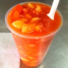 a plastic cup filled with soup on top of a table