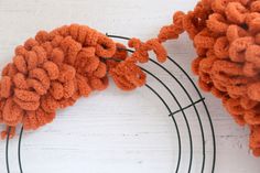 two orange pom poms sitting on top of a wire rack next to each other