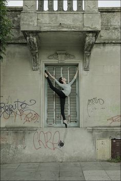 a person jumping up into the air with their arms outstretched in front of a building