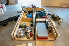 an open drawer filled with lots of items on top of a wooden floor in a garage