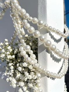 a bunch of pearls hanging from the side of a white building with flowers in front of it