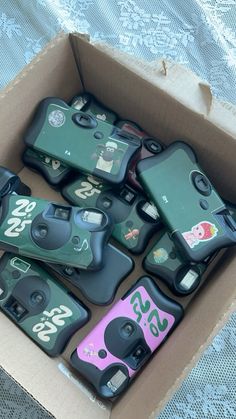 a box filled with lots of cell phones sitting on top of a bed next to each other