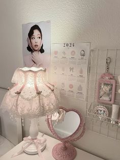 a pink lamp sitting on top of a white desk next to a mirror and calendar