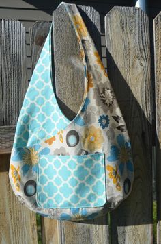 a purse hanging on the side of a wooden fence with a flowered bag attached to it