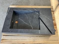 a black marble sink sitting on top of wooden pallets