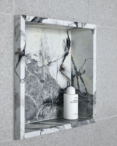 a white bottle sitting on top of a marble shelf