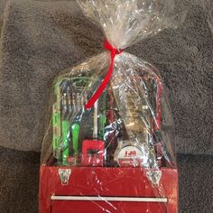 a red toolbox with tools wrapped in plastic on top of carpeted flooring