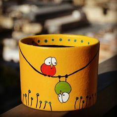 a yellow cup with birds painted on it