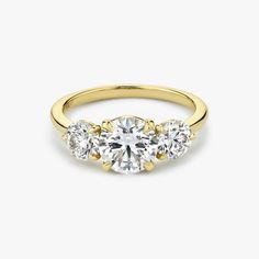 three stone engagement ring in yellow gold with diamonds on the sides and an oval diamond center