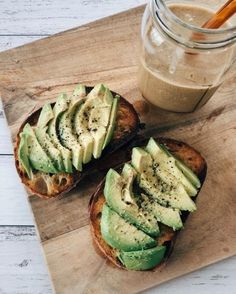 two pieces of bread with avocado on them and a jar of peanut butter