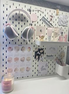 a white desk with headphones on it and a candle in front of the wall