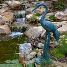 a statue of two birds standing next to a pond filled with water lilies and lily pads