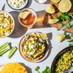 mexican food and drinks on a table with limes, cilantro, tortilla bread