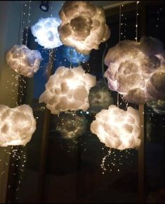 some clouds that are hanging from the ceiling in front of a window with lights on them