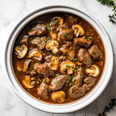 a white bowl filled with meat and mushrooms