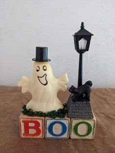 a small halloween decoration on top of blocks with a lamppost in the background and boo spelled out