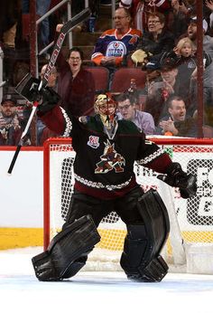 a hockey goalie holding his arms up in the air while standing on the ice