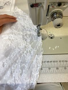 someone is using a sewing machine to sew lace on a piece of white fabric