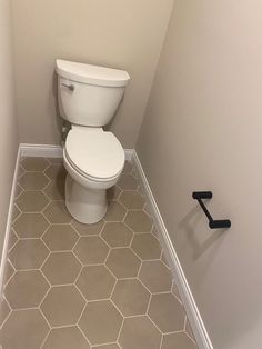 a white toilet sitting in a bathroom next to a black towel rack on the wall