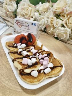 pancakes with marshmallows and chocolate drizzled on them are sitting on a white plate