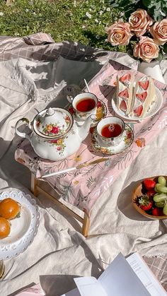 tea and fruit on a table outdoors with pink roses in the backgroung