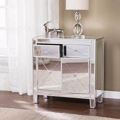 a mirrored cabinet with two drawers and a lamp on the side table in front of a window